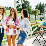 group of friends having outdoor garden barbecue laughing with al