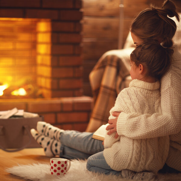 family mother and child hugs and warm on winter evening by fireplace