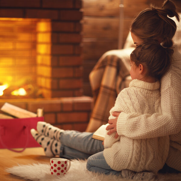 family mother and child hugs and warm on winter evening by fireplace