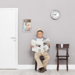 Senior sitting in a lobby and reading newspaper