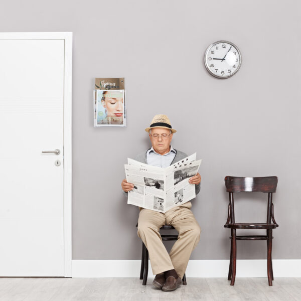 Senior sitting in a lobby and reading newspaper