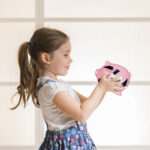 Portrait of happy young little girl looking at her pink piggy ba