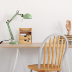 Pile of books, wooden hand and industrial mint colored lamp on s