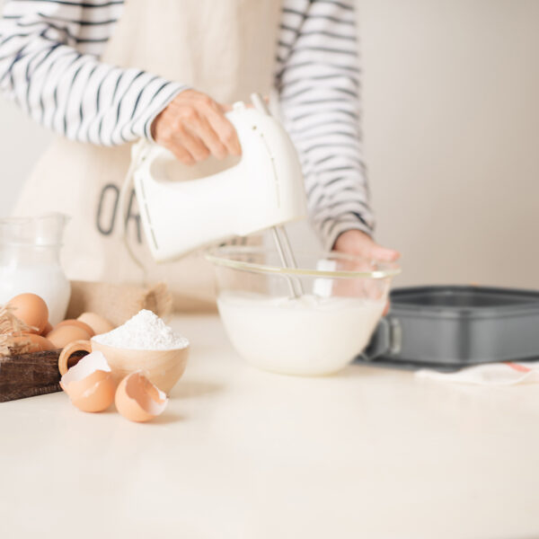 Mixing white egg cream in bowl with motor mixer, baking cake
