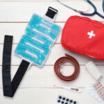 Flat lay composition with first aid kit on white wooden table, s