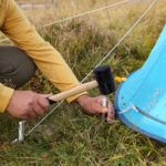 Man setting up camping tent outdoors, closeup