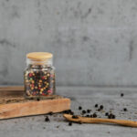 Glass jar of spices on a wooden stand isolated on a grey backgro