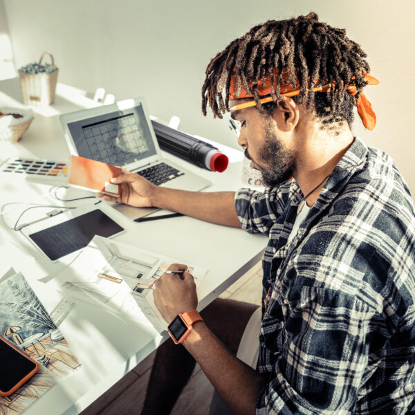 Interior designer with dreadlocks wearing red headband drawing sketches