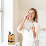 Beautiful young woman removing makeup at home