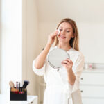 Beautiful young woman removing makeup at home