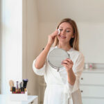 Beautiful young woman removing makeup at home