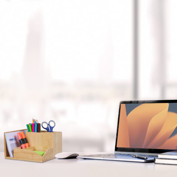 Sideview of office desktop with blank laptop and various office tools on wood desk.