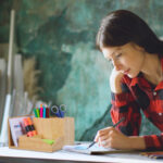 Portrait young woman artist painting scetch on paper notebook with pencil