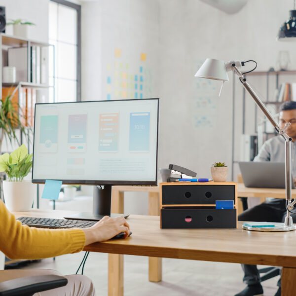 Over the Shoulder: Female Mobile Software Developer Sitting at H