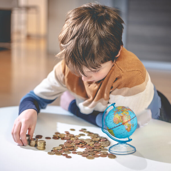 Boy sitting by a table, counting his saved up money.